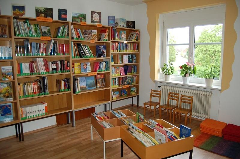 Kinderbereich: Büchertröge, Kindersessel, Pölster an der Wand und große Bücherregal