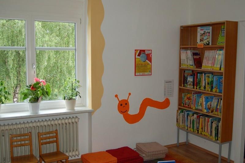 Kinderbereich mit Regal, 2 Kindersessel vor einem Fenster und Pölster an der Wand