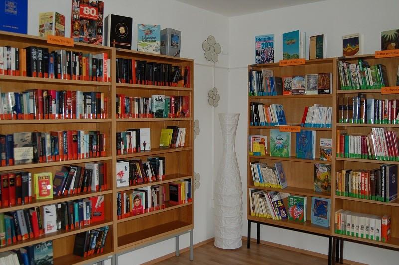 Bücherregale rechts und links von einer Ecke. In der Ecke steht eine hohe Vase.